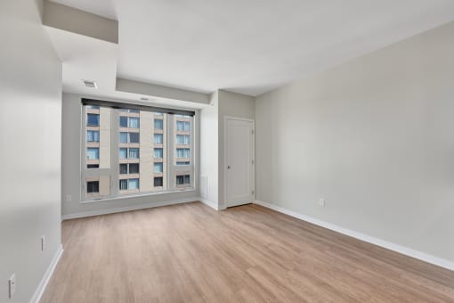 a bedroom with a large window and hardwood floors
