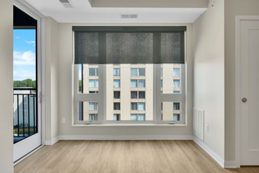 a bedroom with a large window and hardwood floors