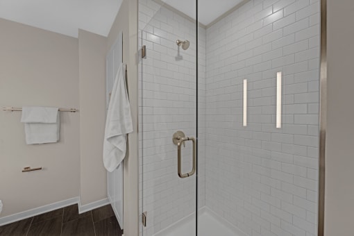 a white tiled bathroom with a shower and a white towel