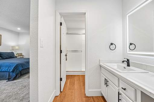 A white bathroom with a blue bed in the bedroom.