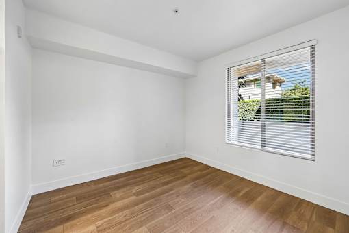 A room with wooden flooring and a window with blinds.