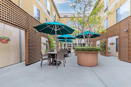 A Patio With Tables And Chairs And Umbrellas at Atrium Garden Apartment Homes, LLC, California
