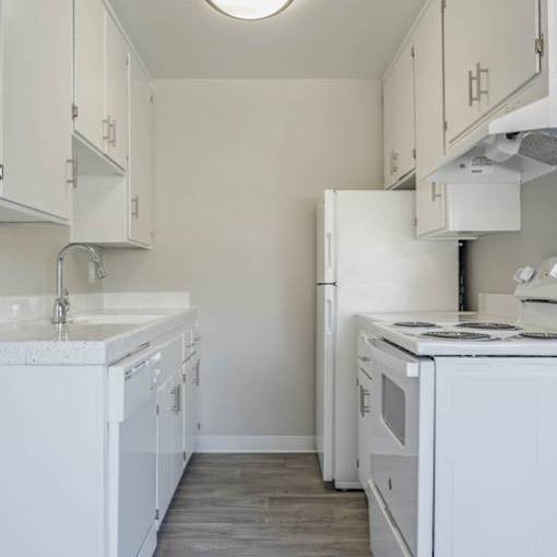 a white kitchen with a stove and a refrigerator at The Arches Apartments, El Cajon, 92021