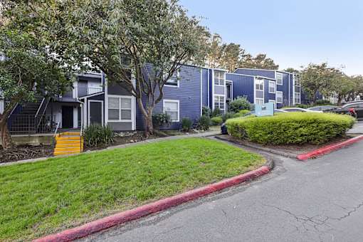 A row of blue apartment buildings with green grass in front. at Skyline Heights Apartments, Daly City