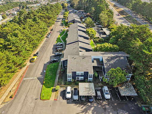 A parking lot with cars and a building in the background. at Skyline Heights Apartments, Daly City, California