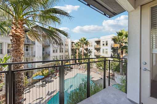 A balcony with a pool and palm trees.