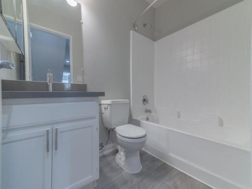 a bathroom with a toilet and a tub and a sink at Warner Center Townhomes, California