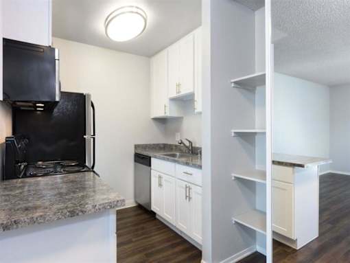 a kitchen with white cabinets and a black refrigerator at Skyline Heights Apartments, Daly City, CA