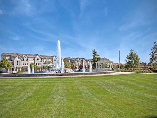 a fountain in the middle of a park with a building in the background at The Vines at Riverpark, LLC, Oxnard, 93036