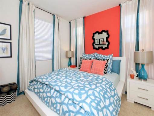 a bedroom with a bed and a red wall and white curtains at The Vines at Riverpark, LLC, Oxnard, CA 93036