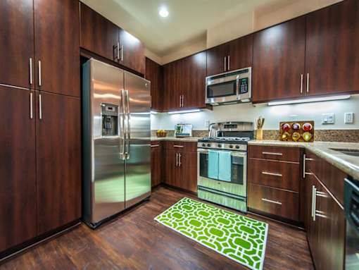 a kitchen with stainless steel appliances and wooden cabinets at The Vines at Riverpark, LLC, Oxnard California