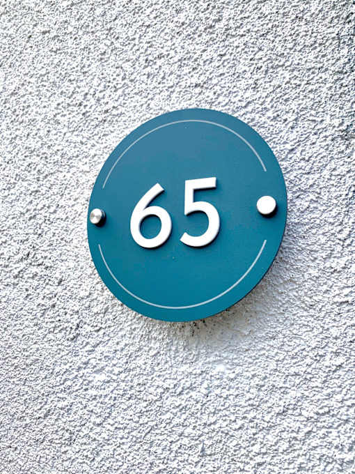 a blue sign with the number 65 on a white wall