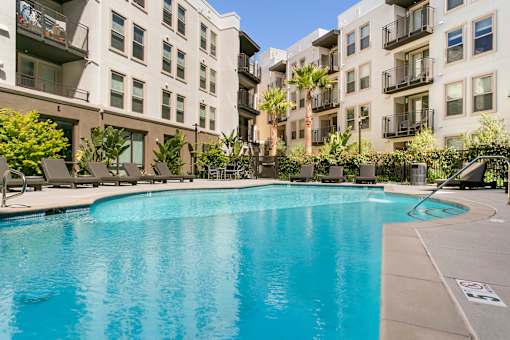 A swimming pool in front of apartment buildings. at Cirrus Redwood City Apartments, Redwood City, CA, 94061