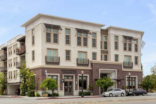 A modern two story building with a parking lot in front. at Cirrus Redwood City Apartments, Redwood City