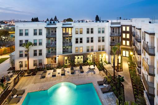 A swimming pool in front of apartment buildings at dusk. at Cirrus Redwood City Apartments, California