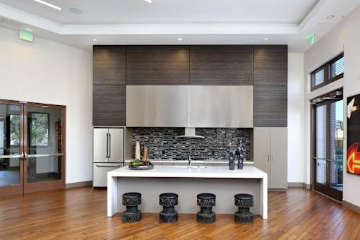 A modern kitchen with a white countertop and black stools. at Cirrus Redwood City Apartments, Redwood City