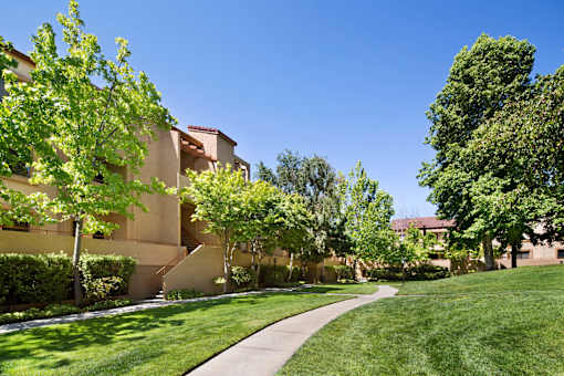 A building with a green lawn in front of it. at The Maddox Sunnyvale Apartments, Sunnyvale