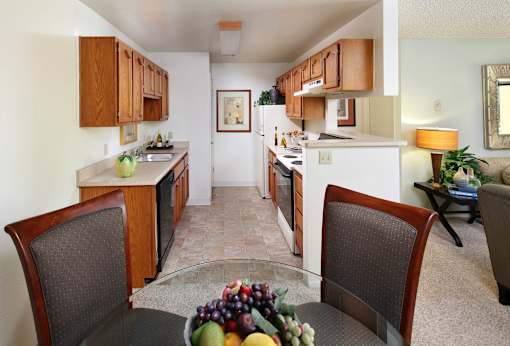 A kitchen with a table and chairs in the foreground. at The Maddox Sunnyvale Apartments, Sunnyvale