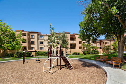 A playground with a slide and a swing set in front of apartment buildings. at The Maddox Sunnyvale Apartments, Sunnyvale, California