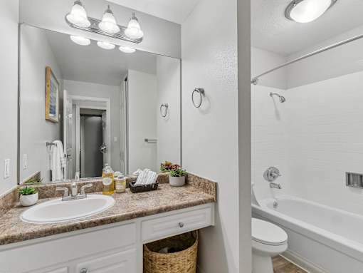 a bathroom with a sink and a mirror and a tub at Summerwood Apartments, Santa Clara, CA 95050