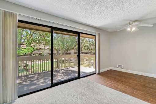 an empty living room with sliding glass doors to a balcony at Summerwood Apartments, California
