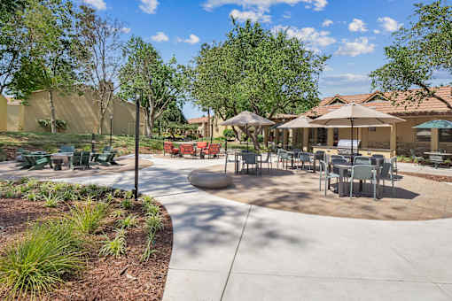 a patio with tables and chairs and umbrellas at Summerwood Apartments, Santa Clara