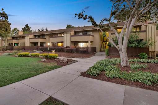 a building with a sidewalk and trees in front of it at Summerwood Apartments, Santa Clara, 95050