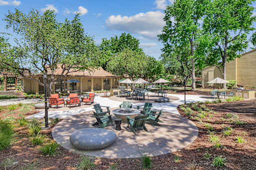 an outdoor patio with tables and chairs and trees at Summerwood Apartments, Santa Clara, 95050