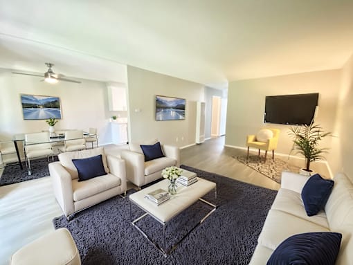 A living room with white furniture and a black flat screen TV.