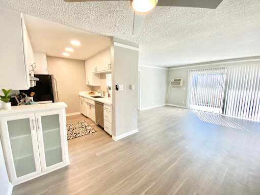 an empty living room and kitchen with a sliding glass door at The Flats on Addison, Sherman Oaks, CA