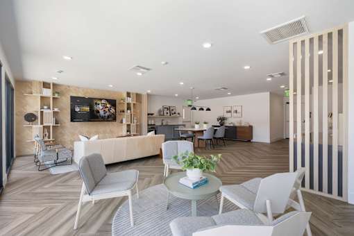 A modern living room with a grey sofa, white chairs, and a coffee table at Latitude Apartments at Mission Valley Apartments, San Diego, CA