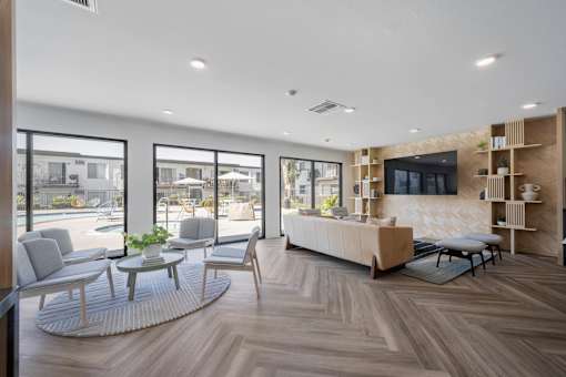 A modern living room with a large window overlooking a pool and patio area at Latitude Apartments at Mission Valley Apartments, San Diego