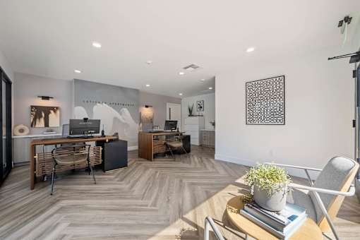 A modern office space with a wooden floor and a large desk with a laptop and a plant on it at Latitude Apartments at Mission Valley Apartments, San Diego, 92120