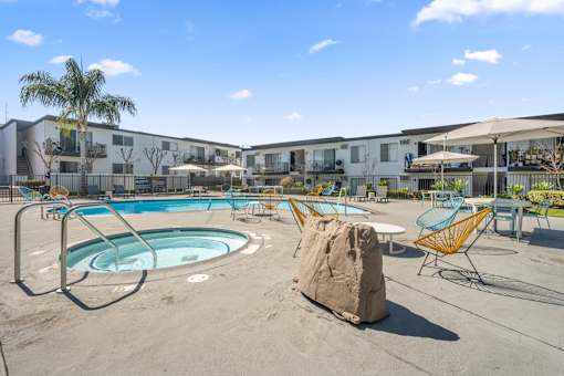 A swimming pool surrounded by chairs and a rock at Latitude Apartments at Mission Valley Apartments, San Diego, CA, 92120