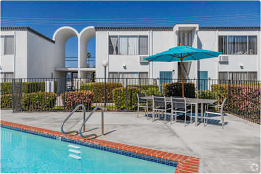our apartments have a swimming pool and a patio with a table and umbrellaat The Arches Apartments, LLC, El Cajon California