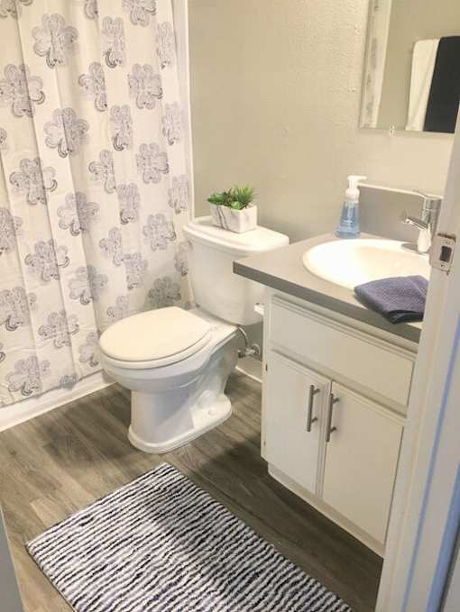 a bathroom with a toilet and a sink and a shower curtain  at The Marq Apartments LLC, Los Angeles