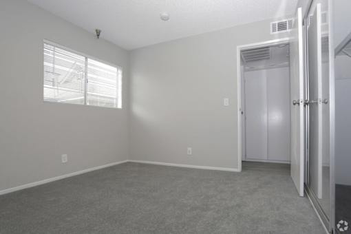 an empty bedroom with a closet and a window  at The Marq Apartments LLC, California