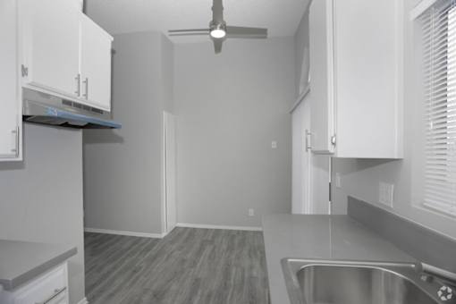 a kitchen with white cabinets and a ceiling fan  at The Marq Apartments LLC, Los Angeles, California