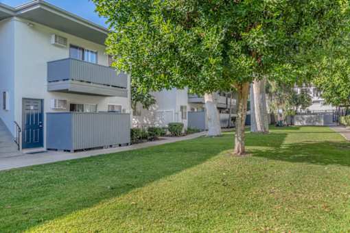 an apartment building with a lawn and trees in front of it at BLVD Apartments LLC, Tarzana, CA