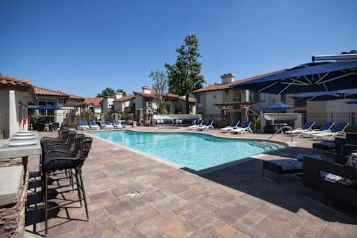 a swimming pool with chairs and umbrellas at The Bryant, California, 92887