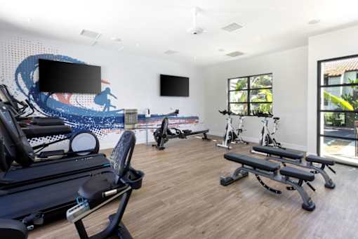 a gym with cardio equipment and a wall mural of the beach at La Jolla Blue, San Diego California