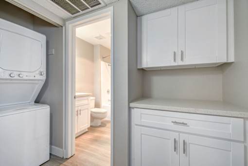 a laundry room with white cabinets and a white washer and dryer at La Jolla Blue, San Diego California