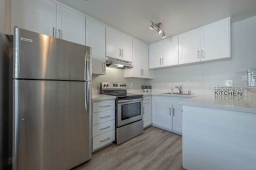 a white kitchen with stainless steel appliances and white cabinets at Napa Green Apartments LLC, California