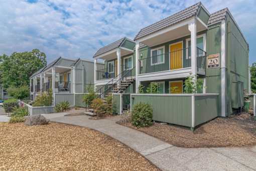 a row of green houses with yellow doors and a sidewalk at Napa Green Apartments LLC, California