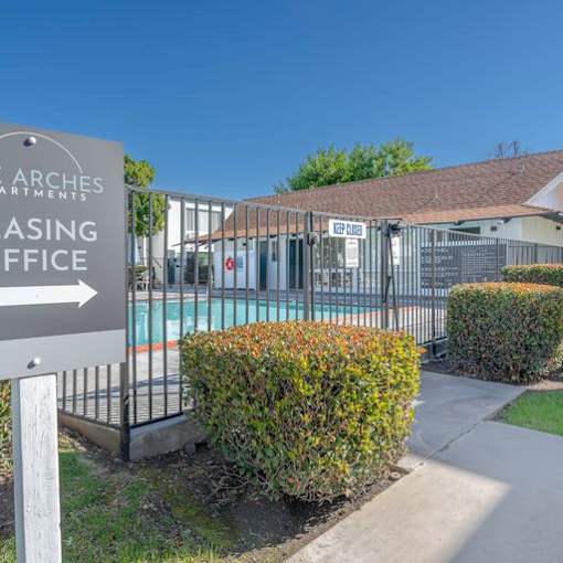 a building with a sign in front of a pool at The Arches Apartments, El Cajon