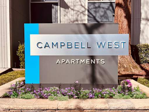 a sign that says apartments in front of flowers at Campbell West Apartments, California