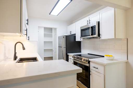 A kitchen with white cabinets and black appliances at Summerwood Apartment , California, 95050