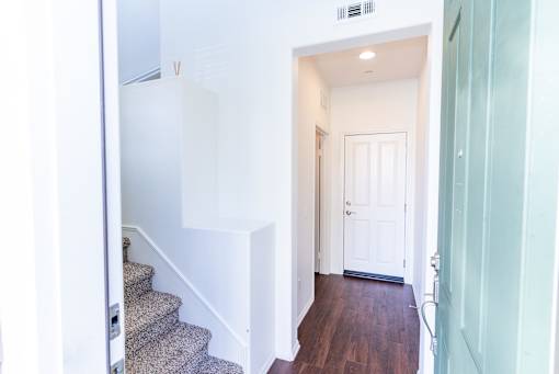 a view of the hallway of a home with stairs and a white door at The Vines at Riverpark, LLC, California, 93036