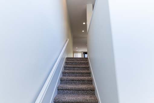 a view down the stairs of a hallway with carpeted stairs and white walls at The Vines at Riverpark, LLC, California, 93036