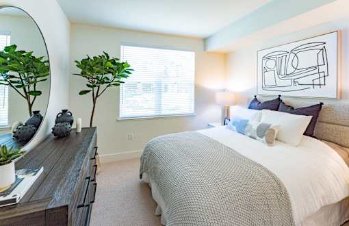A bedroom with a bed, nightstand, and a mirror.